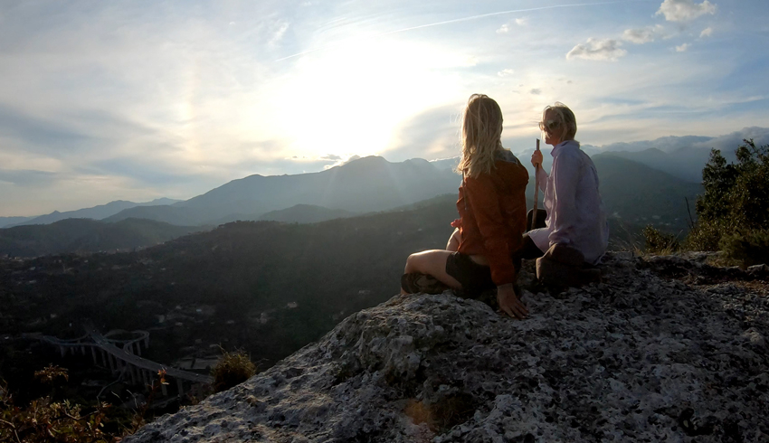 2 women watching the sunset from a mountain top.